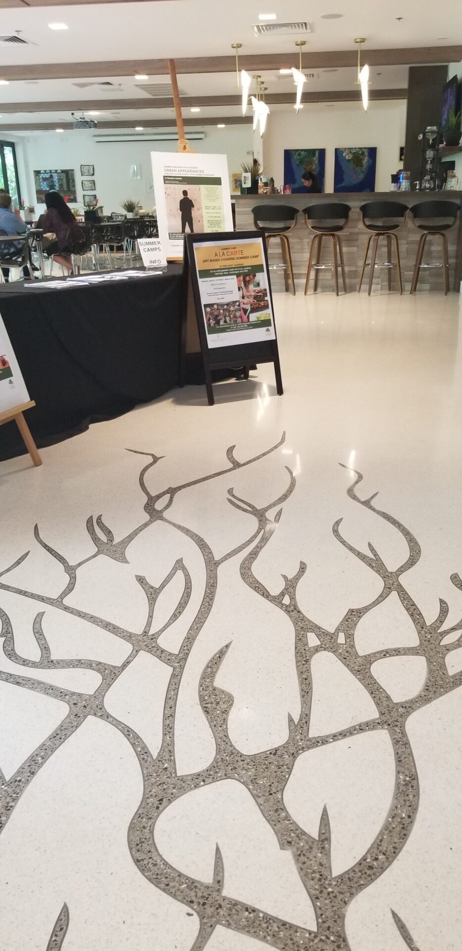 A floor with branches on it and a table in the background.