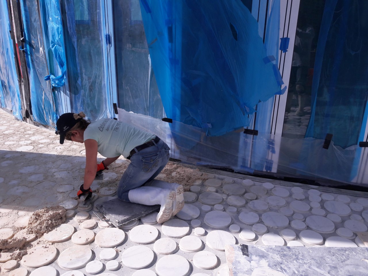 A person kneeling down on the ground with a drill.