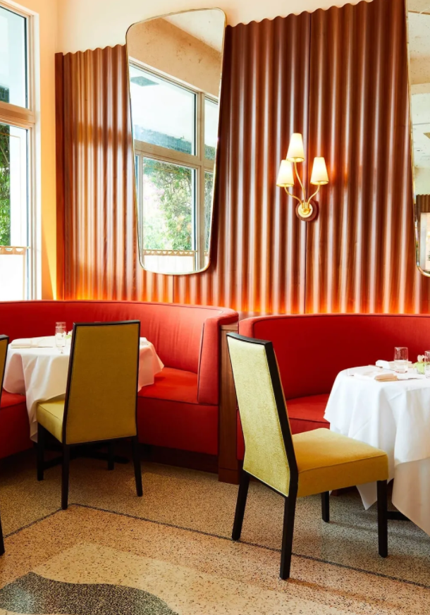 A restaurant with red and yellow chairs, tables and couches.